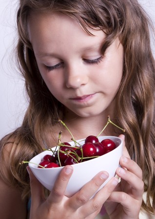 A little girl holding in her hand a cherryの写真素材