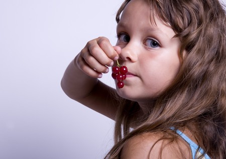 A little girl holding in her hand a cherryの写真素材