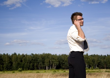 A businessman dressed in a smart suit standing on grassの写真素材