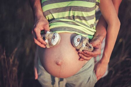 Pregnant woman with husband, holding hands on bellyの写真素材