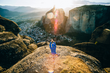 Young fitness woman meditating on sunrise mountain peakの写真素材