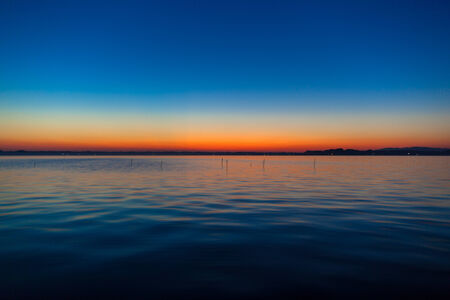 Blue and orange gradation of sunset on the lakeの写真素材