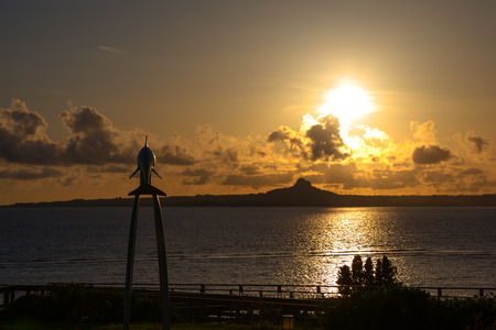 Sunset over the island and dolphin monumentの写真素材