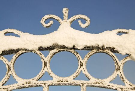 Snow on the wrought iron fence with the blue sky on the backgroundの写真素材