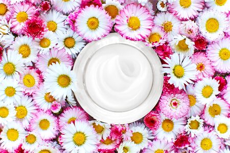 jar of face cream among wildflowers. moisturizing skin care lotion and lifting emulsion. organic cosmetics concept. flat layの写真素材