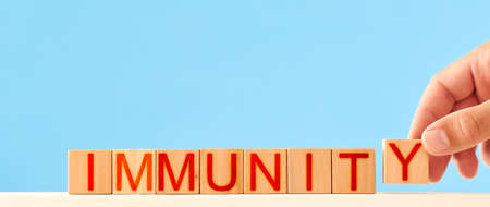 immunity concept. man stacks wooden blocks with the inscription immunityの写真素材