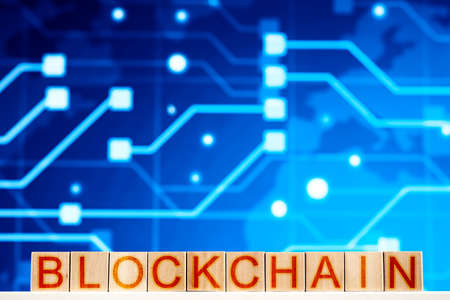 blockchain concept. wooden blocks with the inscription blockchain on a background with a printed...