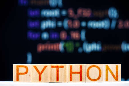 python concept. wooden blocks with python inscription and program code on the background