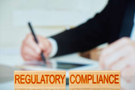 regulatory compliance. wooden blocks with the inscription regulatory compliance with the person...