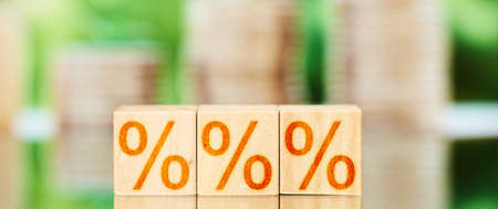 discount concept. wooden blocks with percent icons on a green background with coins.の写真素材