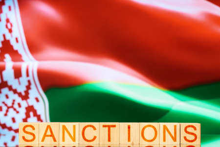 sanctions. wooden blocks with the inscription sanctions on the background of the flag of belarus