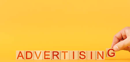 advertising. a man builds wooden blocks with the inscription advertising on an orange background