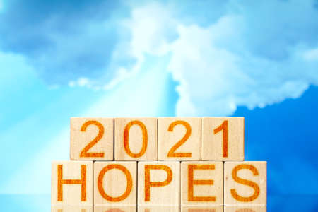 2021 hopes. wooden cubes with the inscription 2021 hopes on a sky background with a ray of light