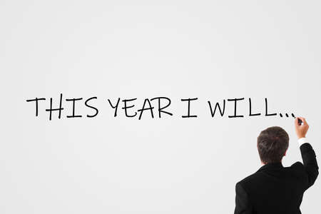 businessman writes on the wall with a marker the inscription this year i will