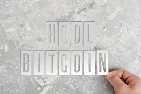 man folds the inscription hodl bitcoin from metal platesの写真素材