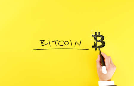 a man draws a symbol bitcoin next to the inscription bitcoin. blockchain and cryptocurrency concept