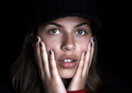 Girl with fingers on the face, black backgroundの写真素材