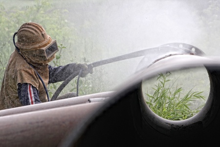 A worker sandblasting the weld during the construction of pipelinesの写真素材