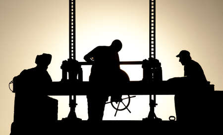 Silhouettes of workers at work in the eveningの写真素材