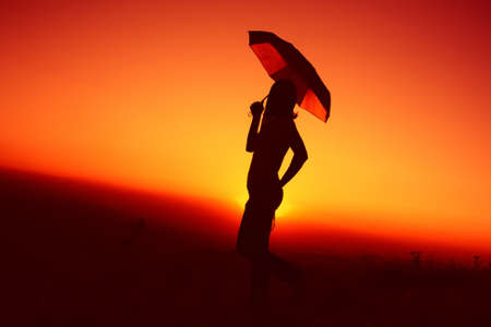 Silhouette of woman with Silhouette of woman with umbrella on sunset on sunsetの写真素材