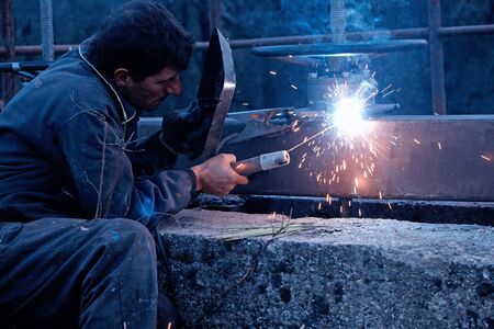A metalworker welding metal construction on the site