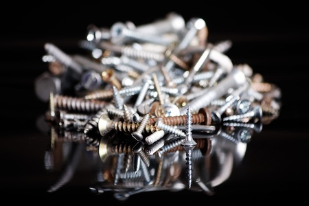 A bunch of different screws on a black backgroundの写真素材