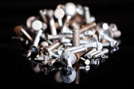 A bunch of different screws on a black backgroundの写真素材