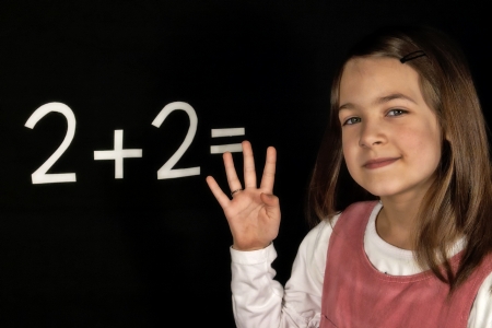 Happy schoolgirl solves the task of the boardの写真素材