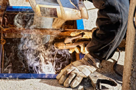 Welder with protective mask welding metal, sparks and smokeの写真素材