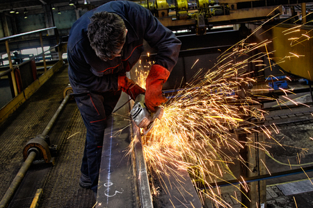 Handyman with electric grinder, grinding steel structure, focus on tools, low Lightの写真素材