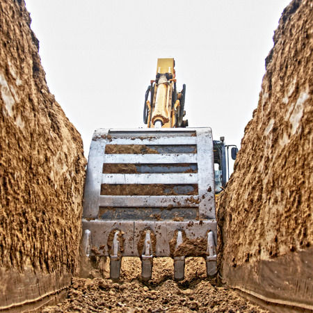 Excavator digging a deep trench on the site, focus forwardの写真素材
