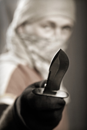 masked man holding a knife on a black background, focus forwardの写真素材