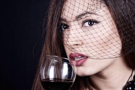 Beautiful woman under the black veil, with wine glassの写真素材