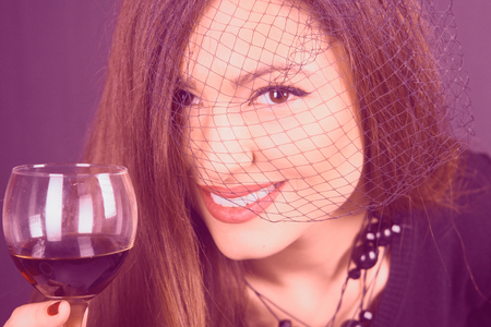 Beautiful woman under the black veil, with wine glassの写真素材