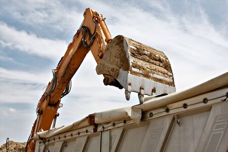 excavator loads the sand of the truck at construction site