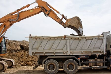 Excavator loader machine during earthmoving works outdoors at construction siteの写真素材