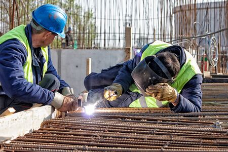Welder at the site welded steel bars, focus on the steel rodsの写真素材