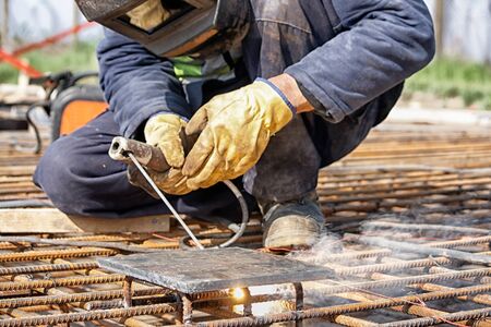 Welder at the site welded steel bars, focus on the steel rodsの写真素材