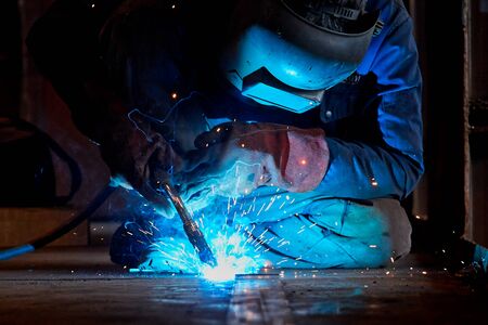Welder working at the factory  in a welding mask and welders leathersの写真素材