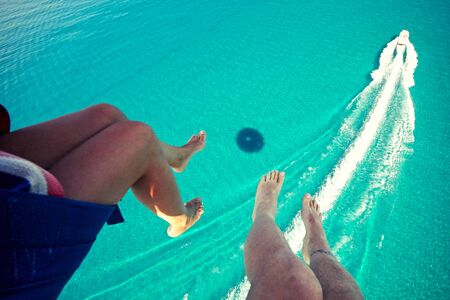 View of feet parasailing with the speed boat in the sea background.の写真素材