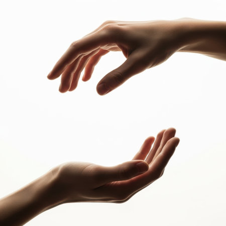 The image depicts two hands reaching towards each other, symbolizing connection, support, and unity. The hands are positioned against a plain white background, emphasizing the interaction between them. The lighting highlights the contours and shadows of the hands, adding depth and a dramatic effect to the composition.の素材