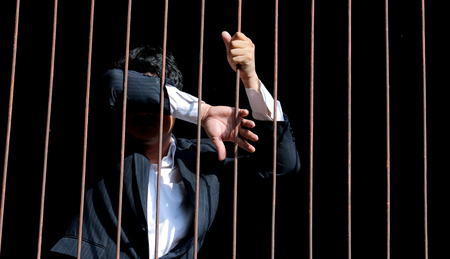 closeup on hands of man sitting in jailの写真素材