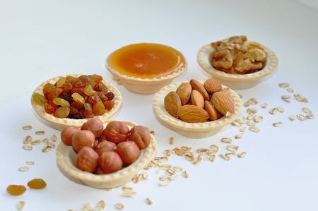 Many different nuts poured into tartlets with honey on a white backgroundの写真素材