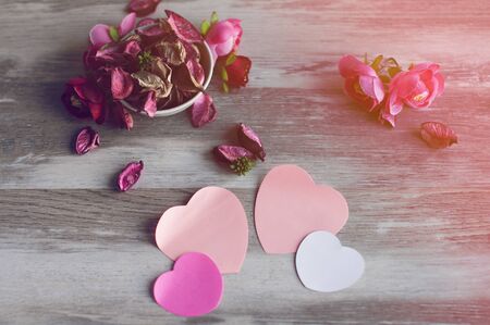 Dry air petals pink roses lie on the table in a white Cup, near with them lie pink paper heartsの写真素材