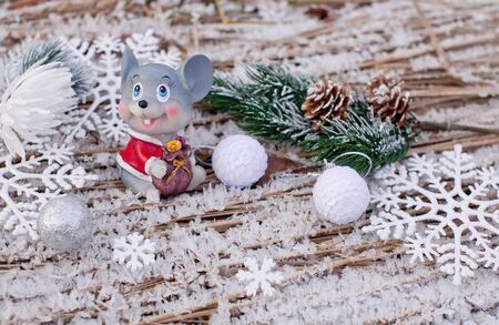 Christmas winter holiday background with frozen grass with ice crystals, a beautiful mouse toy - a symbol of the year, fir branches and cones for banners, cards and postersの写真素材
