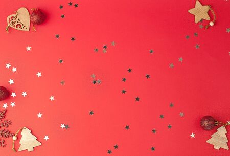 Christmas festive red background with a place for text on which glittering stars and wooden decorative ornaments and Christmas toys lieの写真素材