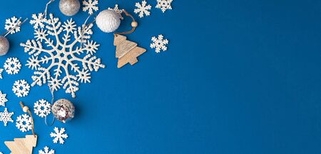 Christmas festive blue background on which are wooden Christmas toys, white snowflakes of different sizesの写真素材