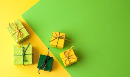 Christmas graphic multi-colored background  from yellow, green and blue paper with a geometric pattern, with gifts and Christmas toys in a package with a scourgeの写真素材
