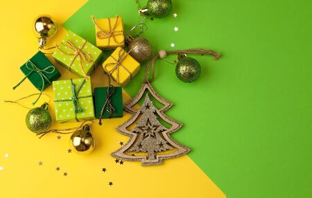 Christmas graphic multi-colored background  from yellow, green and blue paper with a geometric pattern, with gifts and Christmas toys in a package with a scourgeの写真素材