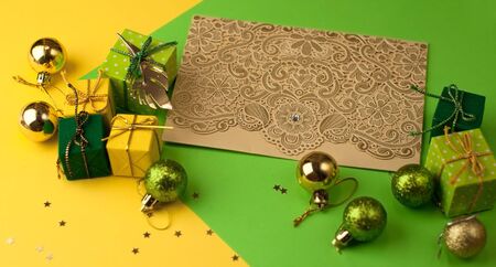 Christmas graphic multi-colored background from yellow, green and blue paper with a geometric pattern, with gifts and Christmas toys and a carved greeting card with a patternの写真素材